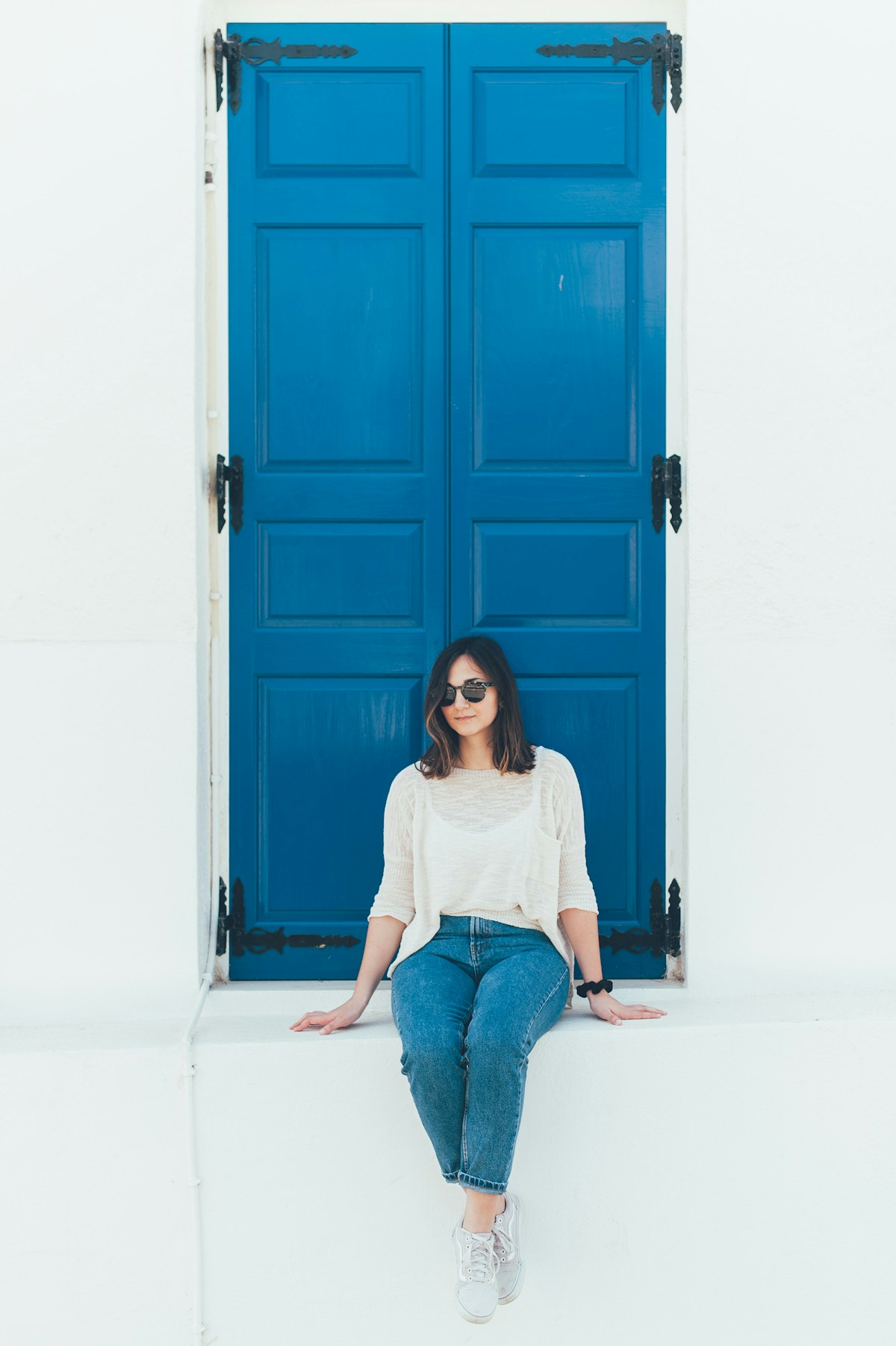 Donna in abito chiaro accanto a una porta blu