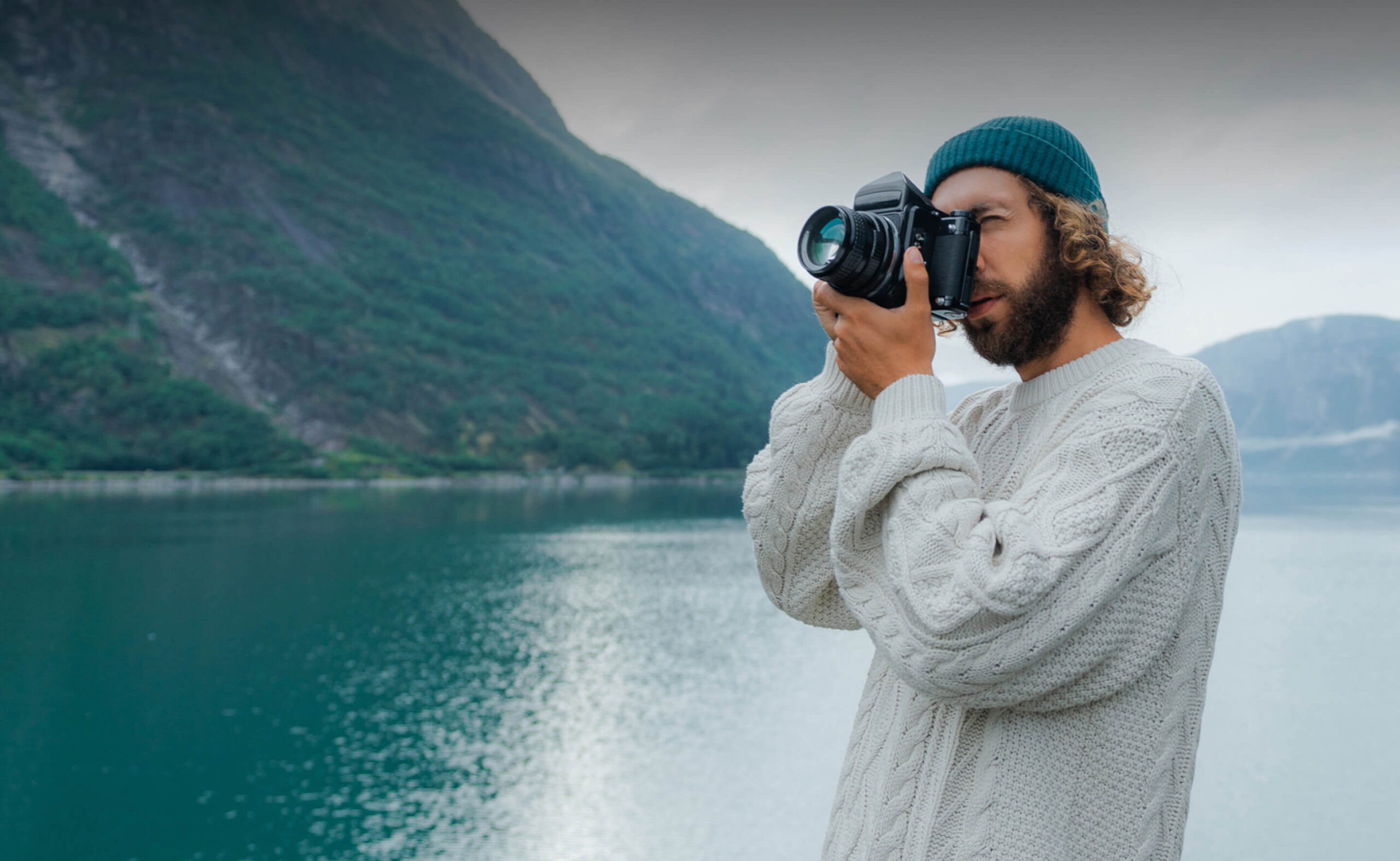 Mann fotografiert eine Berg- und Seenlandschaft