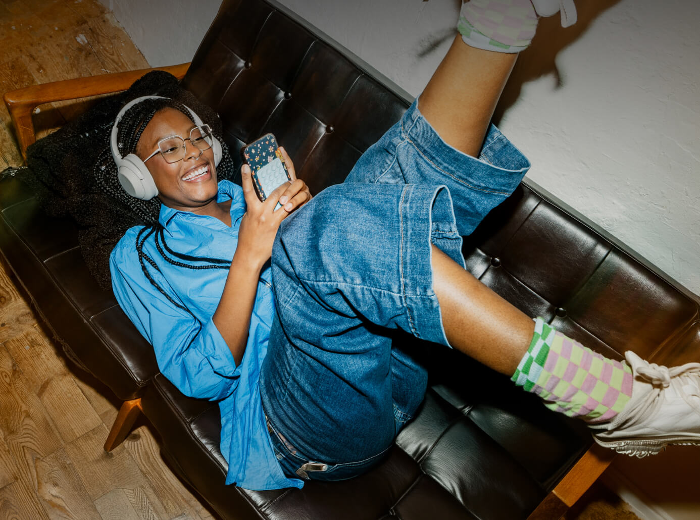 Junge Frau mit Smartphone auf dem Sofa beim Membership-Rewards-Thema