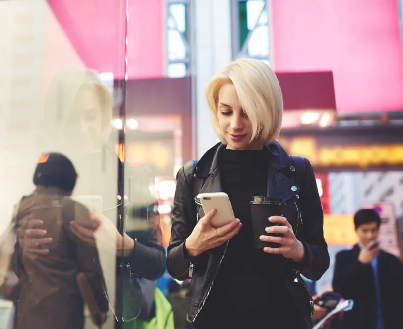 Viaggiatrice con smartphone in un terminal affollato