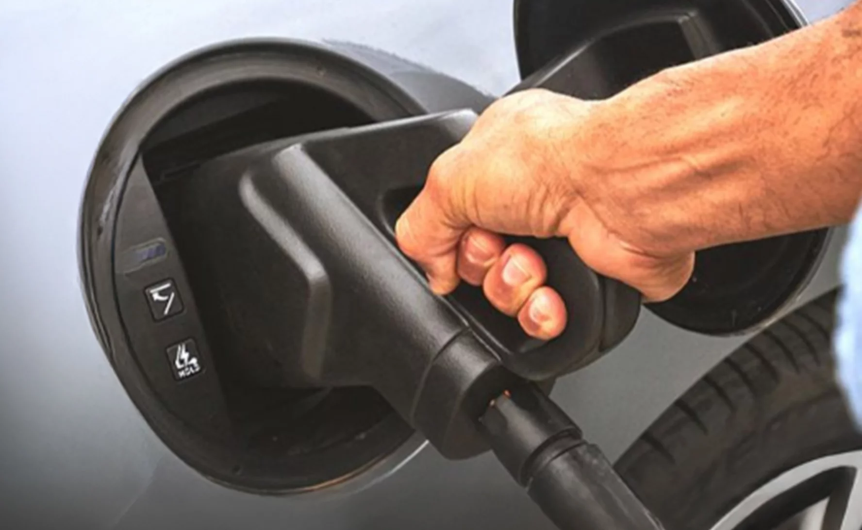 Persona che ricarica un'auto elettrica durante l'estate