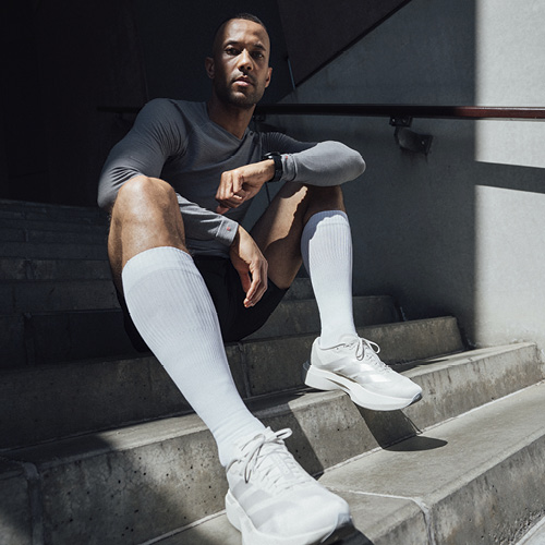 Mann im Sportoutfit trägt FALKE Kompressionsstrümpfe auf einer Treppe