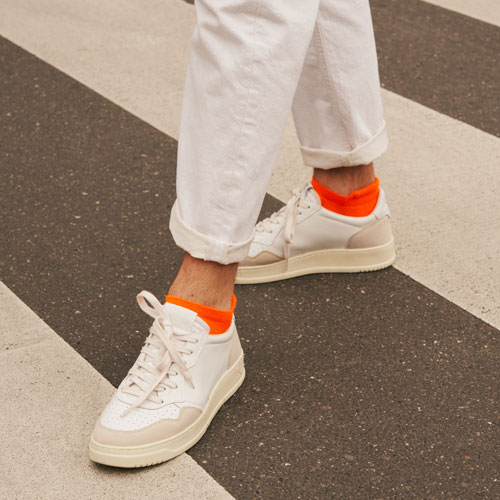 Mann mit orangefarbenen FALKE Cool Kick Sneakersocken auf einem Zebrastreifen