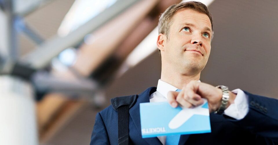Geschaeftsreisender haelt ein Flugticket am Flughafen