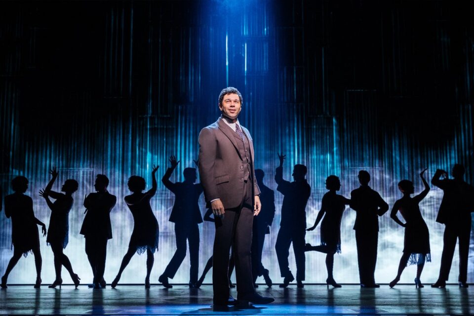 Actors performing The Great Gatsby Broadway musical in an illuminated party scene