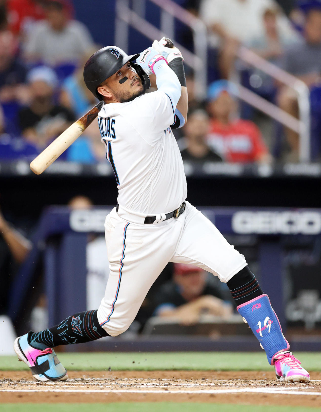 Bateador de Miami Marlins con uniforme blanco y detalles de color en el campo