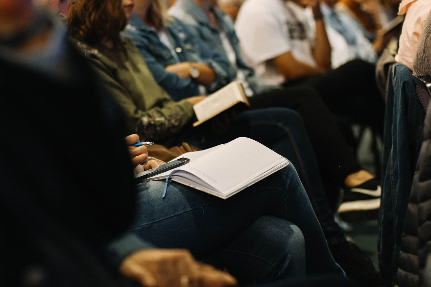 Person writing while seated in an audience
