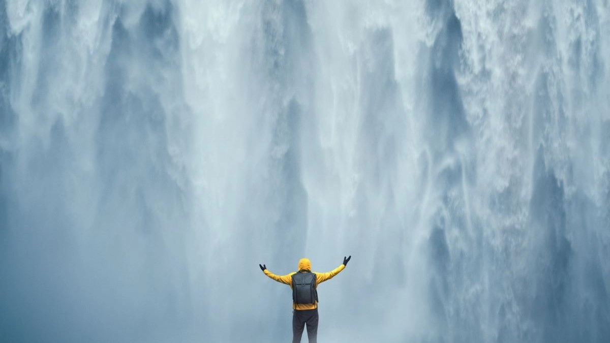 Traveller standing beneath a waterfall