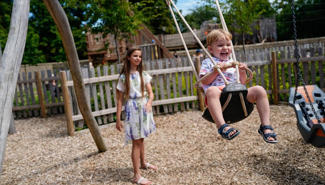 Child laughing on a swing at Blenheim Palace Adventure Play