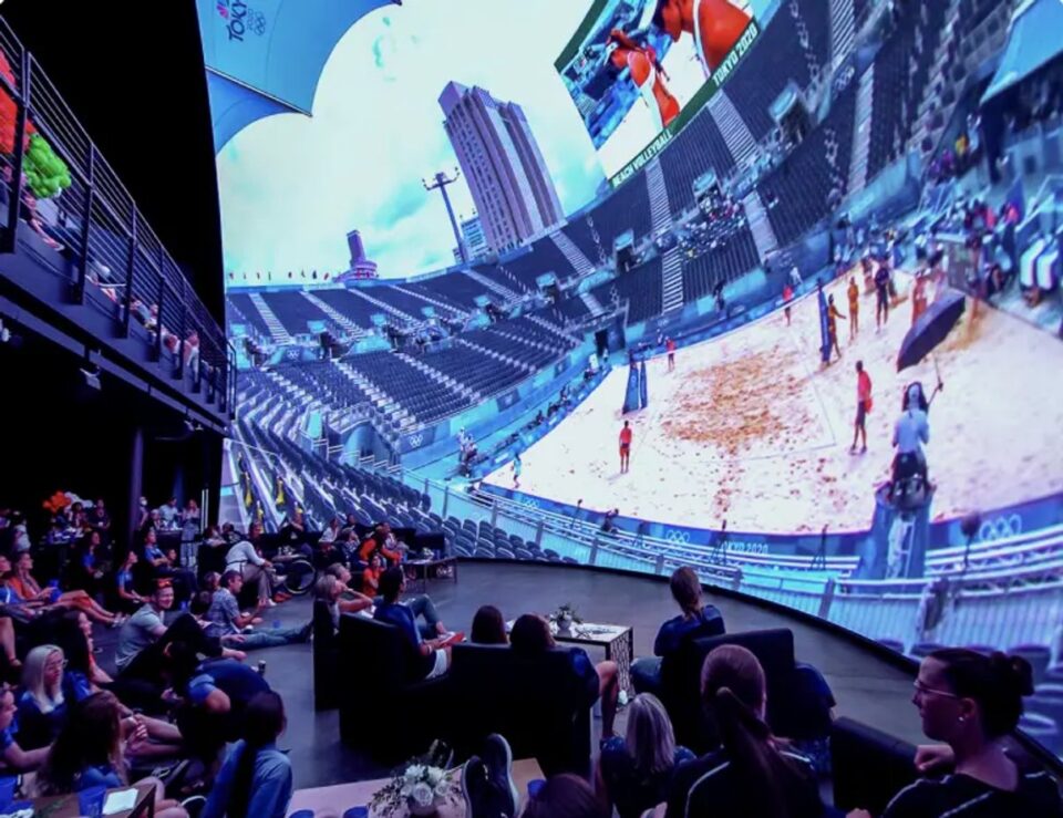 A crowd gathered beneath Cosm's immersive display during a content partnership