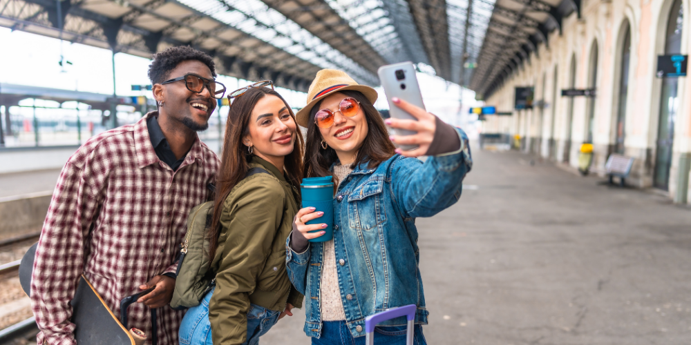 Freunde machen ein Selfie am Bahnhof vor einer gemeinsamen Zugreise