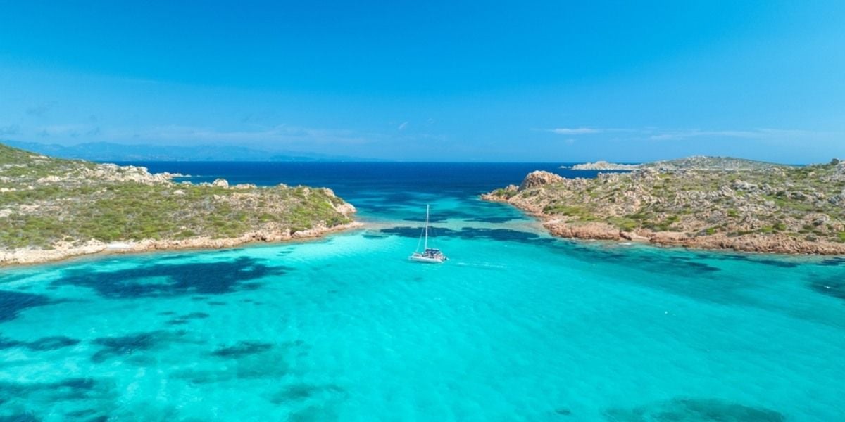 Turquoise Sardinian bay with a sailboat