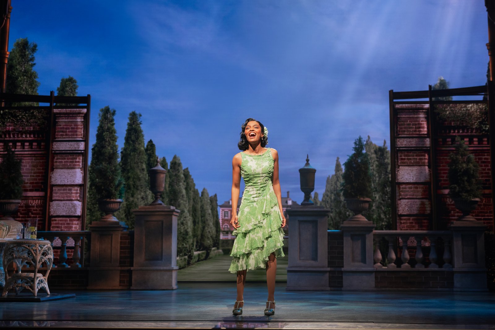 A woman singing in a garden-like stage setting in The Great Gatsby Broadway