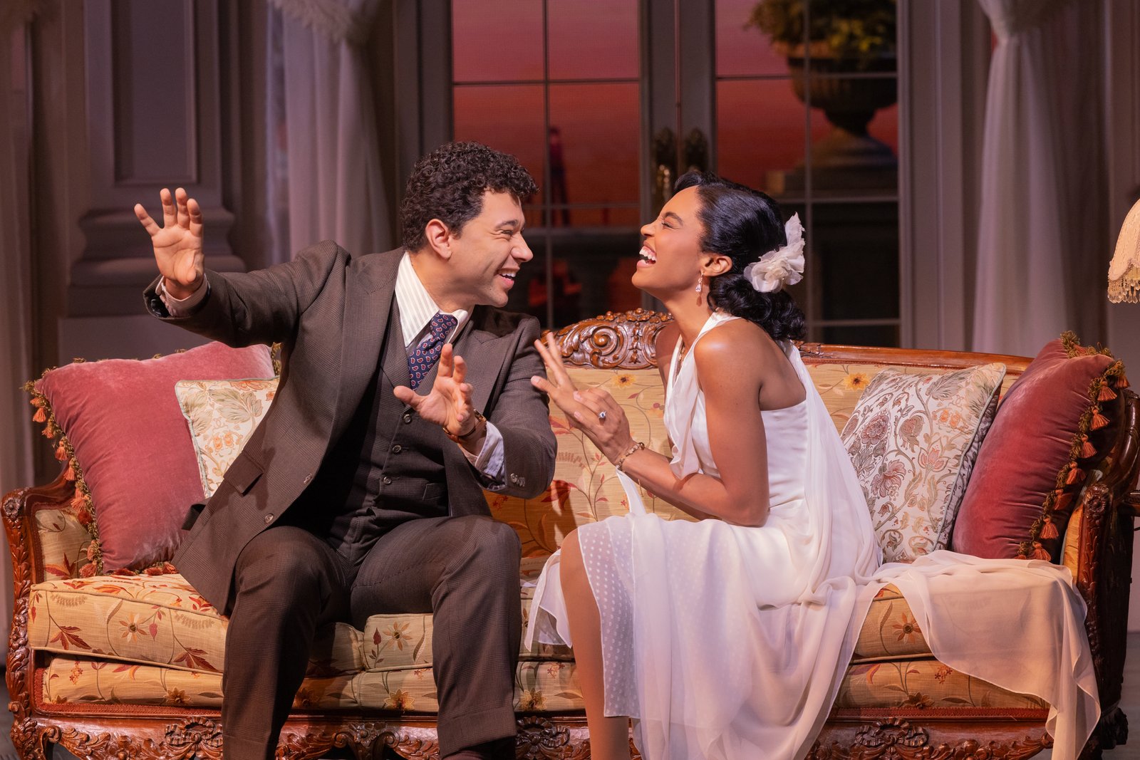 Two actors laughing on a sofa in The Great Gatsby Broadway