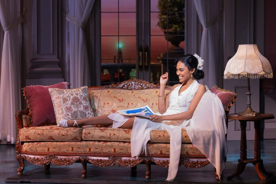 A performer reclining on a stage sofa in The Great Gatsby Broadway