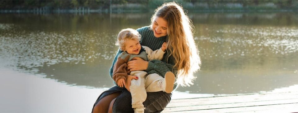 Mutter und Kind an einem See in einer natürlichen Frühlingsszene