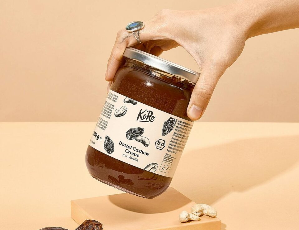 Eine Hand hält ein Glas Bio Dattel Cashew Creme von Korodrogerie