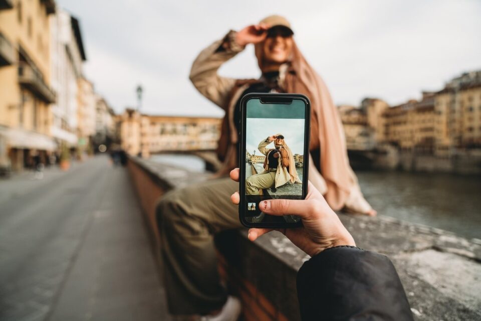 Person being photographed with a smartphone beside a riverside