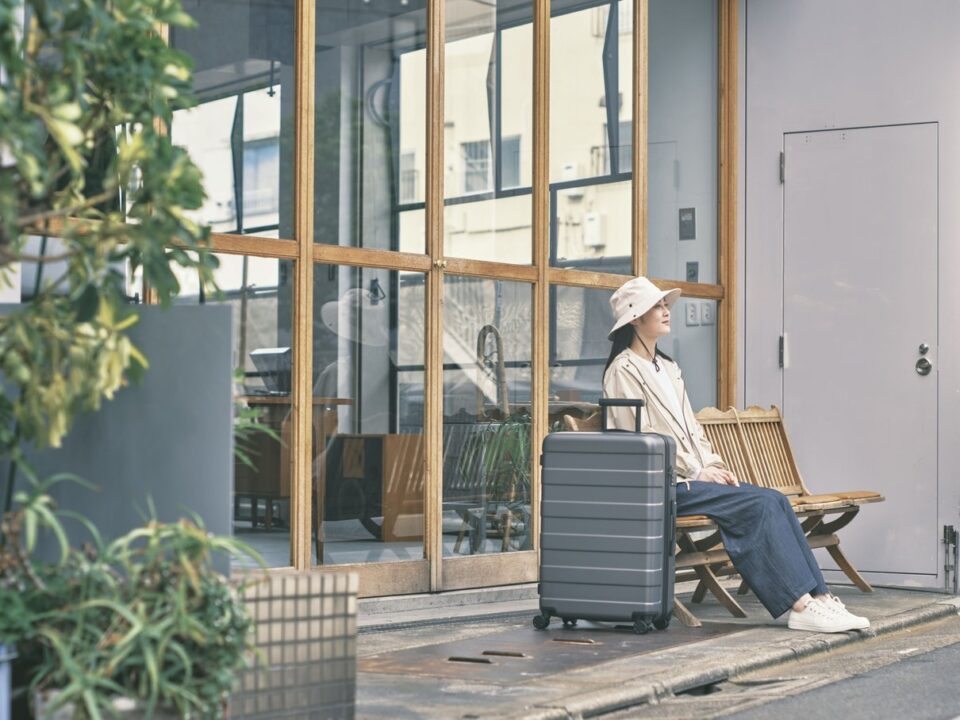 Woman seated with a suitcase outdoors