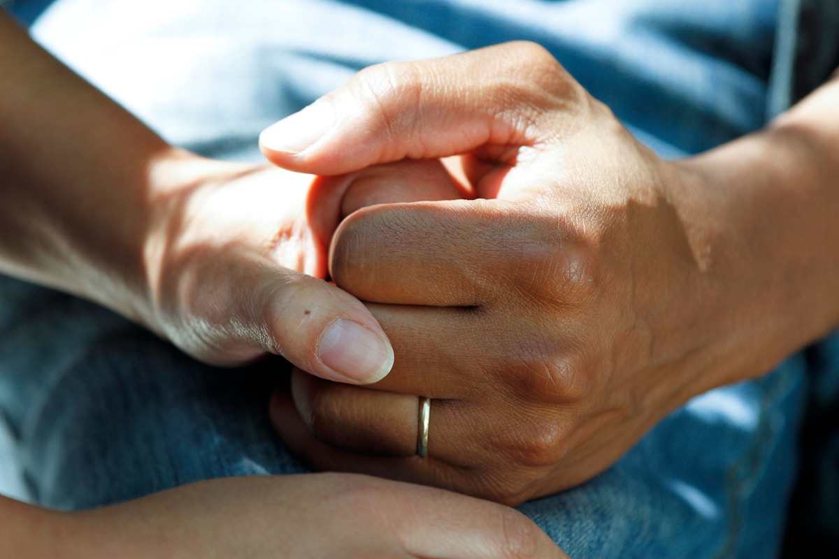 Two pairs of hands holding in a supportive gesture