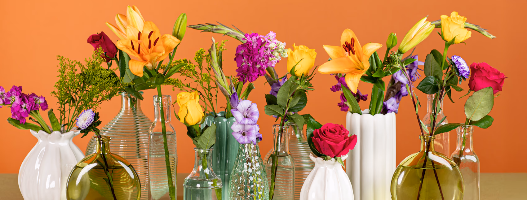 Several flower arrangements in clear green and white vases