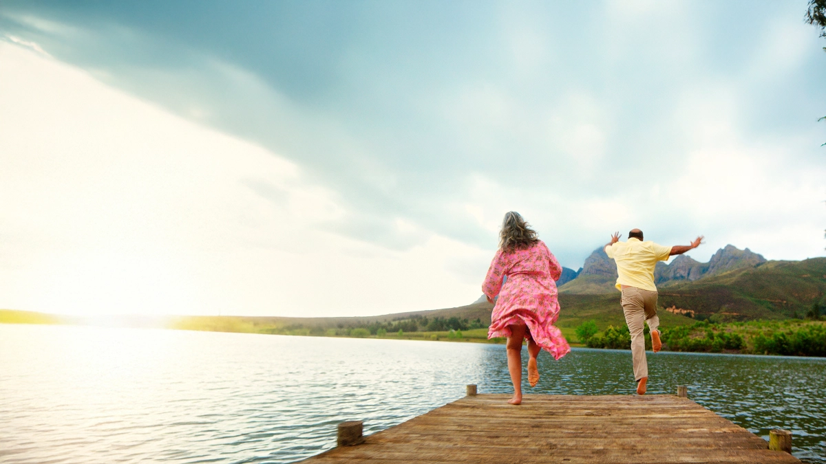Couple running beside a lakeside pier