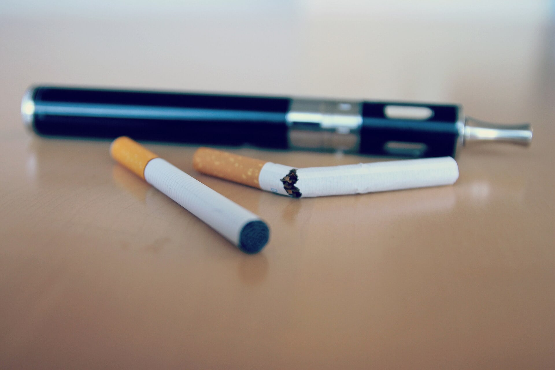 Electronic cigarette beside bottles of e-liquid