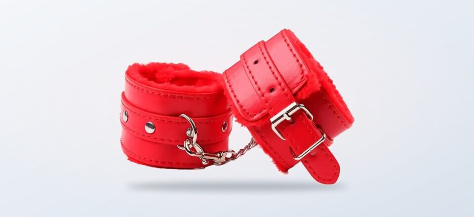 Rote Plüsch-Handschellen von Woome auf hellem Hintergrund
