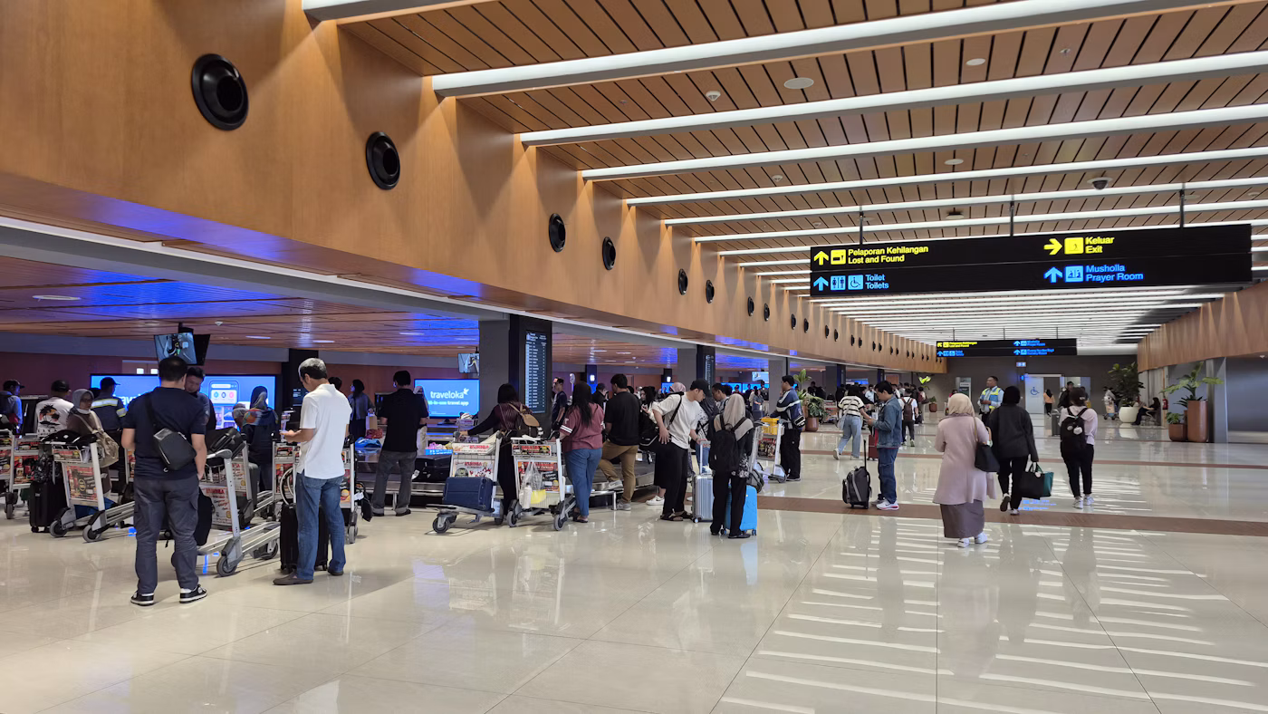People walking through an airport terminal with luggage