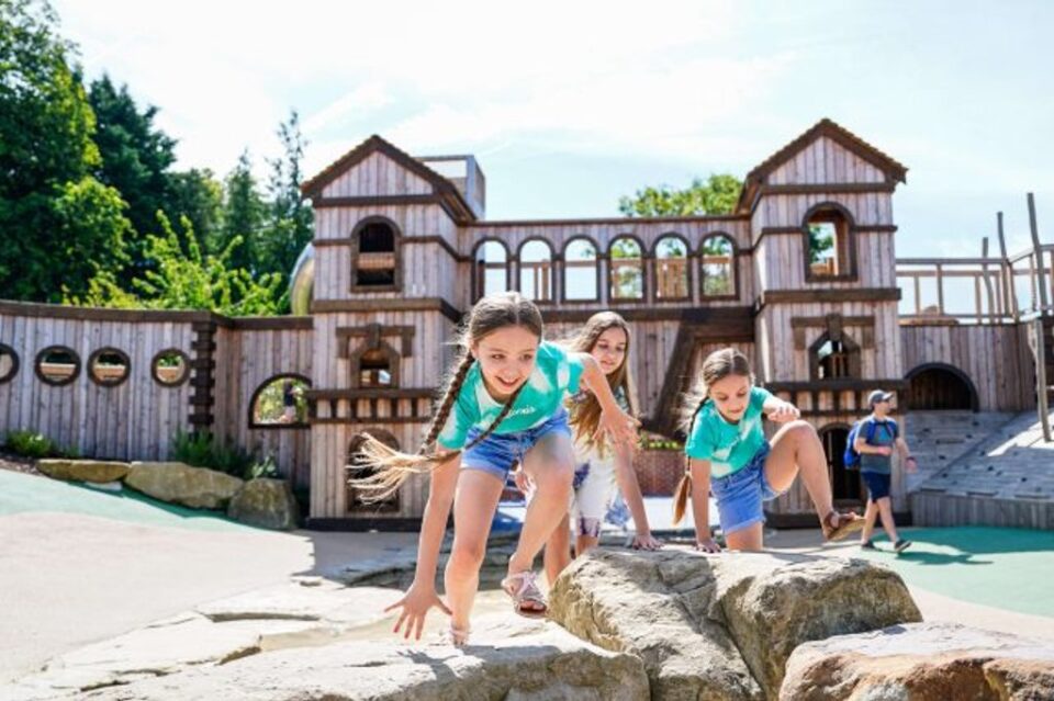 Children climbing rocks beside a wooden play fort