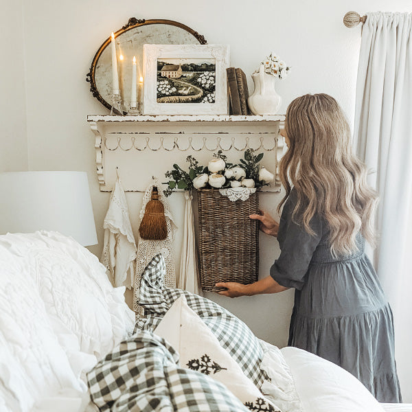Woman styling a distressed white wall shelf with hooks