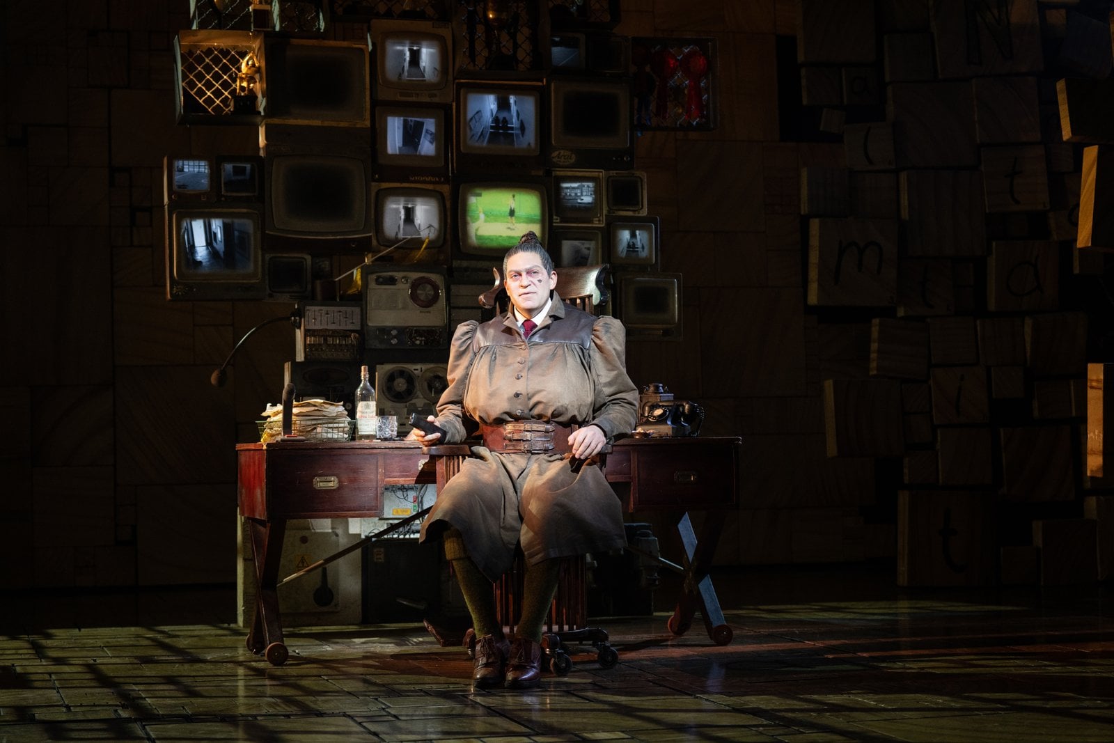 Miss Trunchbull seated at a desk on the Matilda stage
