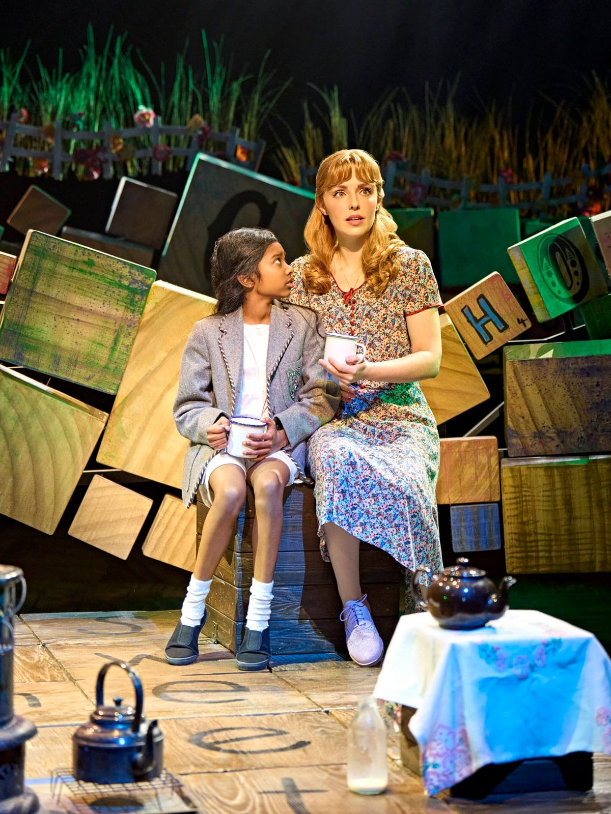 Matilda seated beside Miss Honey on stage