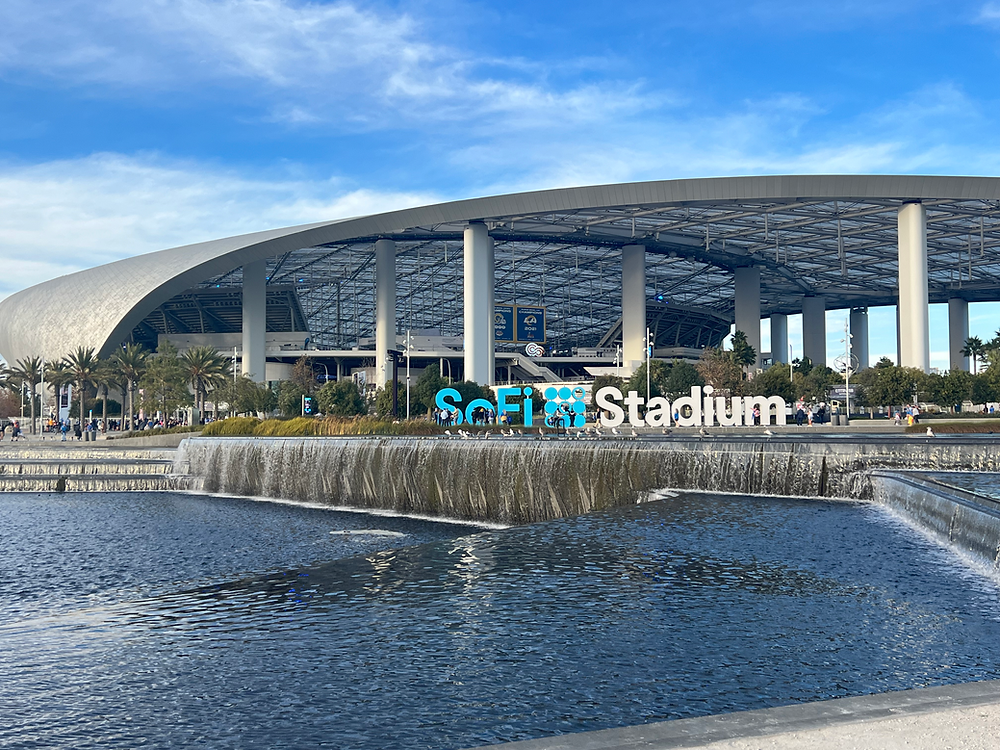 SoFi Stadium entrance plaza with the stadium sign and reflecting pool