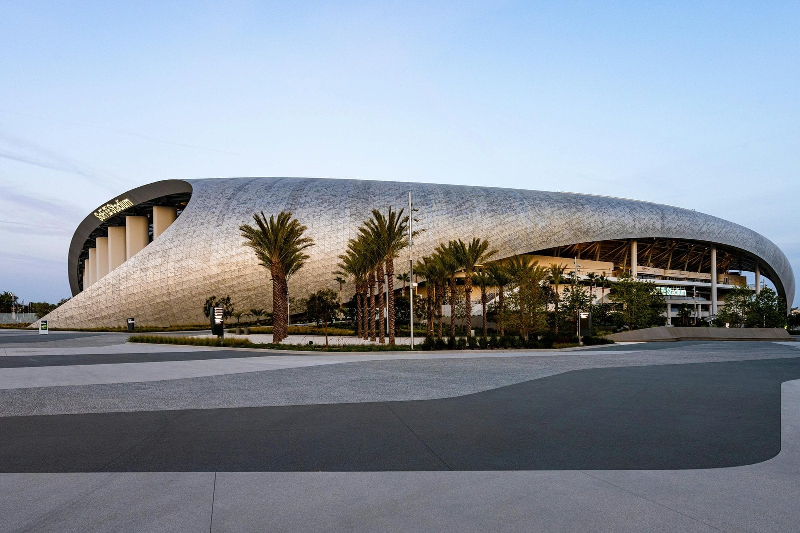 North exterior of SoFi Stadium with its curved roof and palm trees
