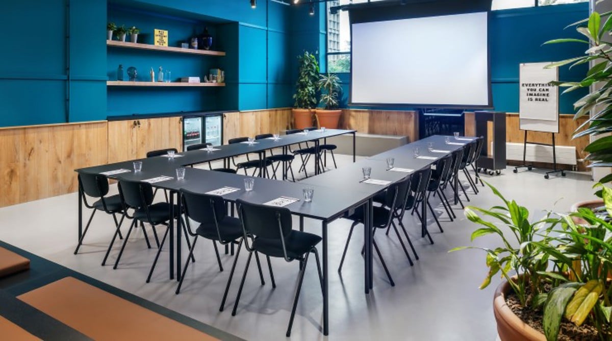 Moderne vergaderruimte van The Social Hub met lange tafels en presentatiescherm